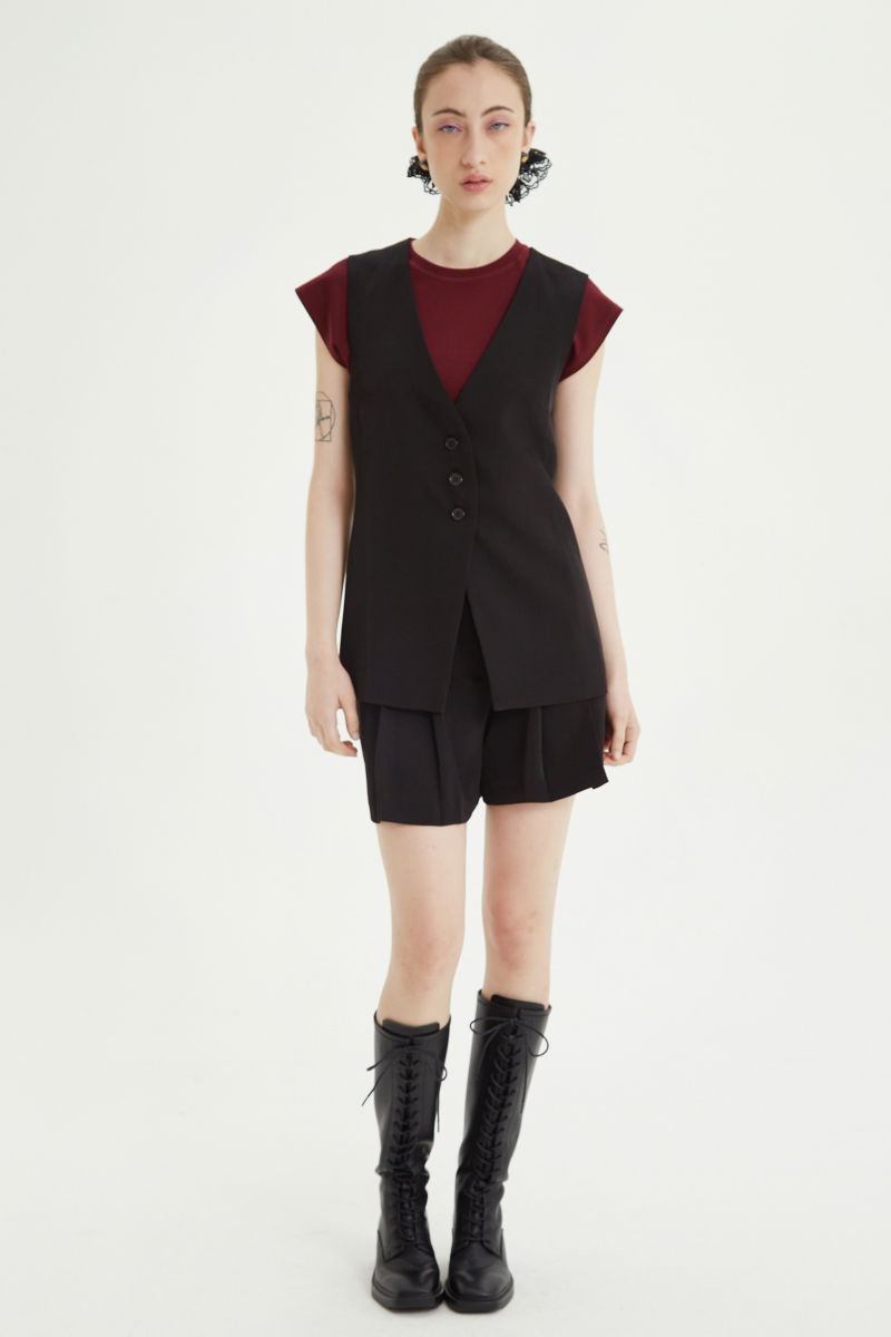 Short negro sastrero con pinzas delanteras, cintura ancha con presillas para cinturón y botones a tono, bolsillos laterales y bolsillos ojal traseros.
