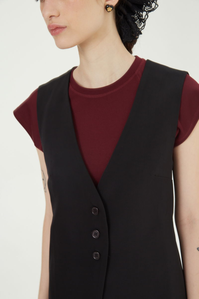 Chaleco sastrero negro con escote en V y largo a la cadera con botones a tono y lazo en la espalda. 