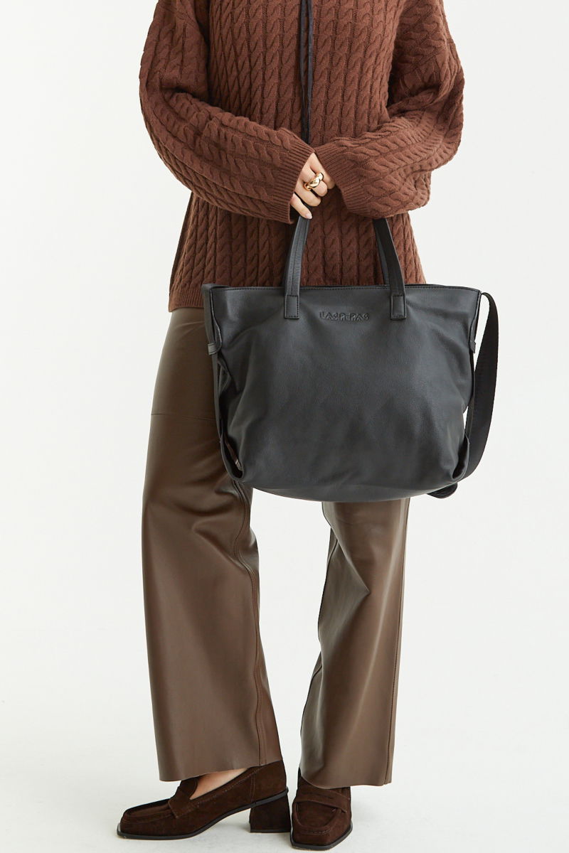 Cartera de cuero estilo shopper con logo grabado al frente, manijas cortas de cuero y correa larga de cinta mochilera.