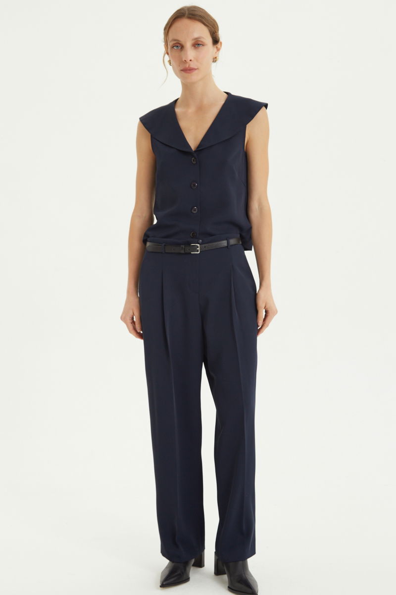 Pantalón azul sastrero tiro alto, de corte recto y largo hasta los tobillos con pinzas de entalle en frente y espalda. 