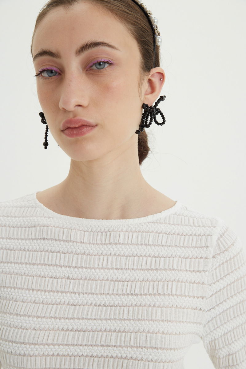 Remera blanca al cuerpo con mangas semi acampanadas, con escote a la base del cuello y textura fruncida. 
