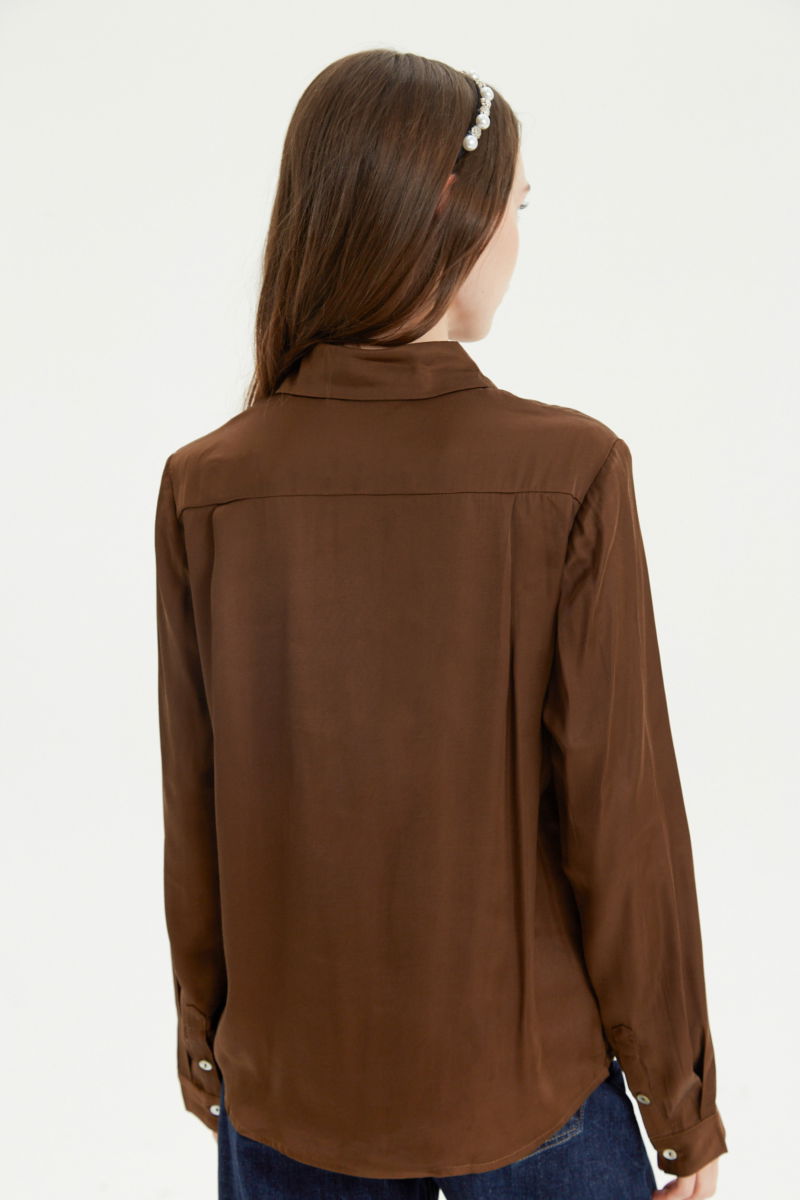 Camisa satinada con botones nacarados a contratono, de corte recto y larga hasta la cadera. 