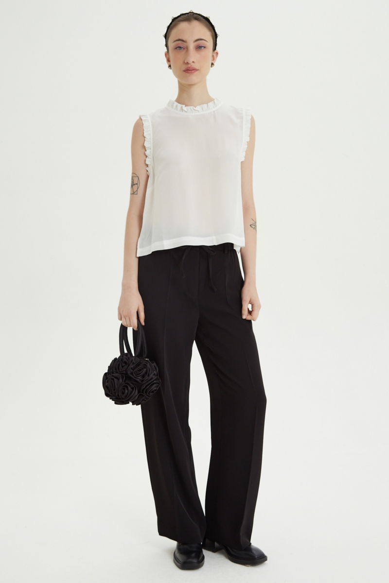 Musculosa cruda de seda con volados en cuello y sisas, de corte recto y larga a la cadera con cuello mao y botones en la espalda. 
