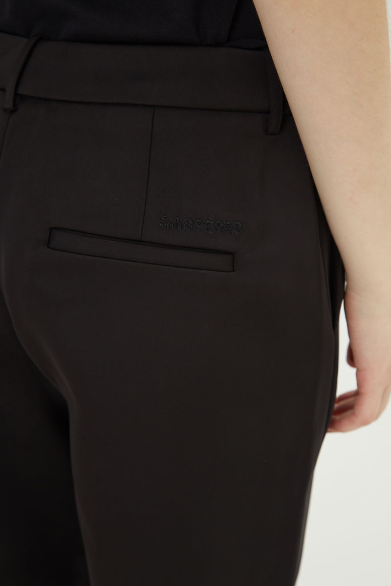 Pantalón negro sastrero satinado tiro medio de silueta recta y largo por encima del tobillo.
