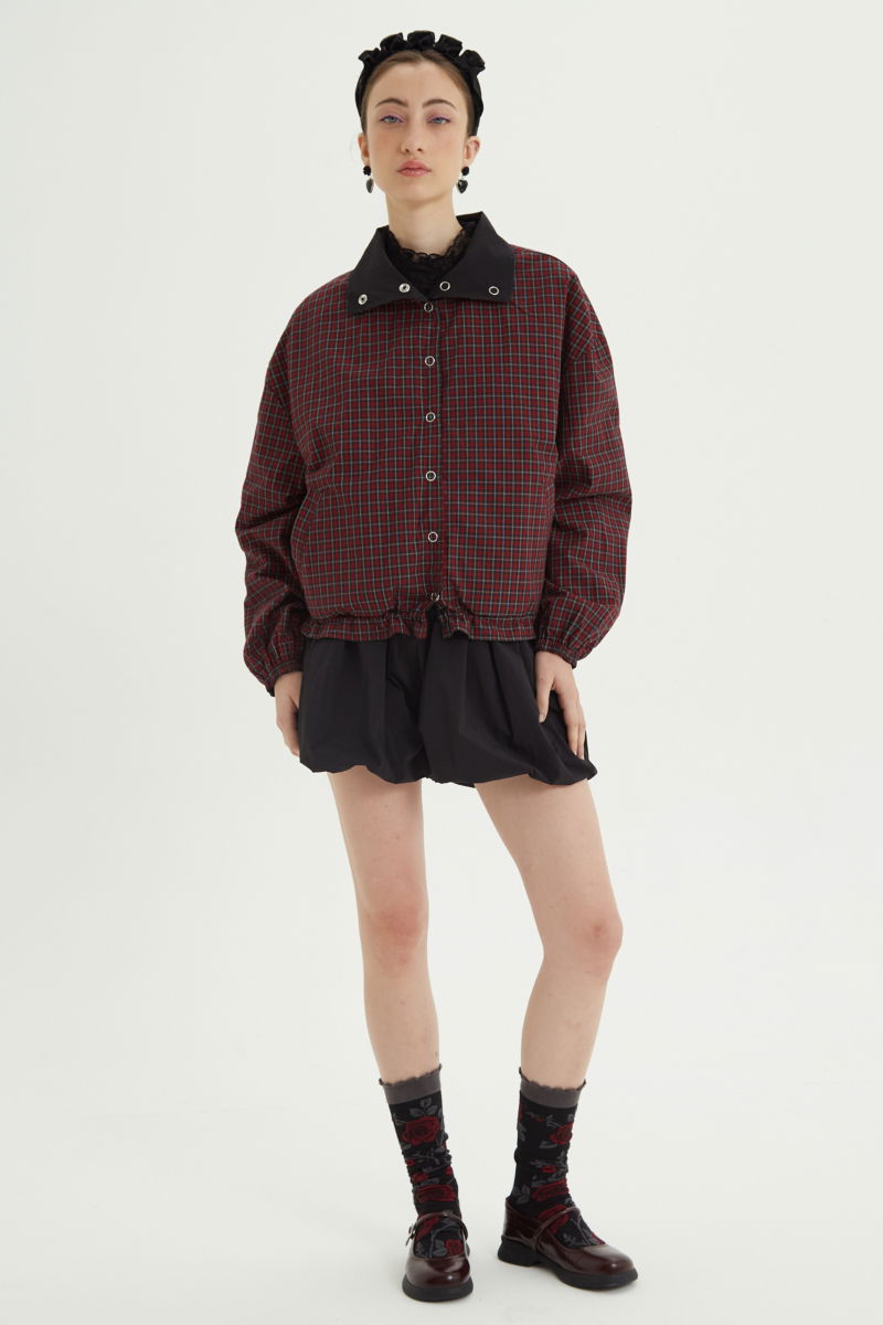 Campera reversible con puntilla y motivo de cuadros, cuello alto, broches snap y cintura con tancas. 
