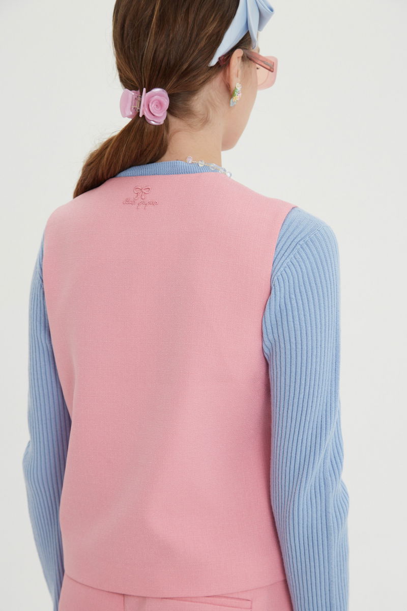 Chaleco rosa sastrero con terminación ondulada y botones a tono. 
