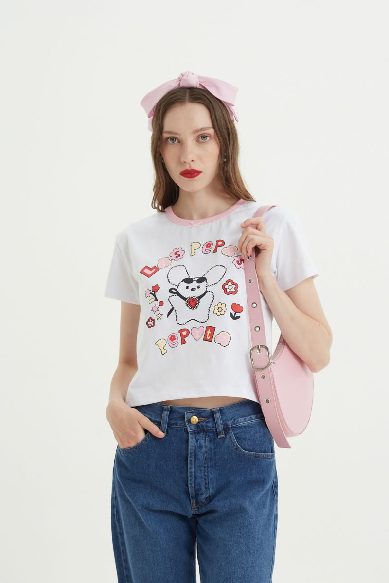 Remera de algodón con estampa central, manga corta, recta y larga hasta la cadera con cuello redondo con terminación de ribb rosa y moño de cinta de raso.