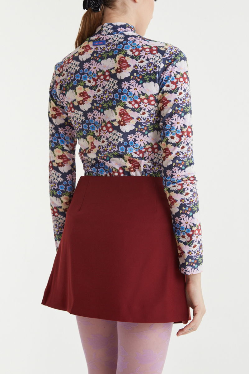 Falda bordo sastrera acampanada con sobre falda tableada con lazo para atar en el lateral. 